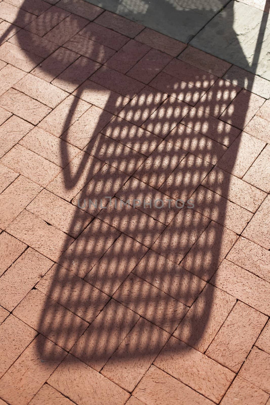 Closeup of Red Brick Sidewalk With a Shadow of a Chair and Table