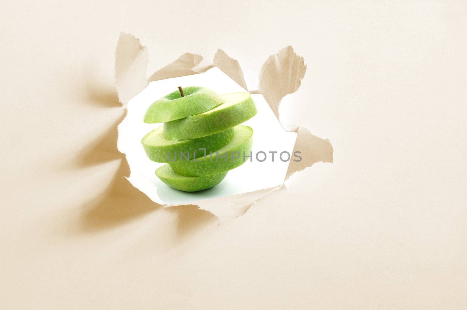 sliced apple fruit behind a hole in blank paper