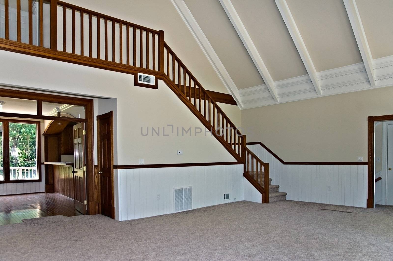 The interior of a newly remodeled house showing the stairway, carpet, ceiling detail and entry to the kitchen area.