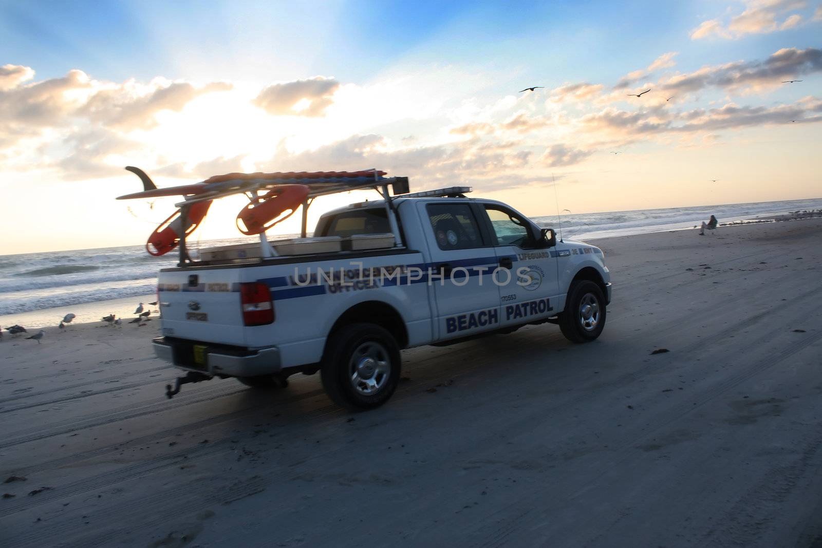 beach patrol drives by as the sun rises over the beautiful atlantic ocean in daytona beach florida
