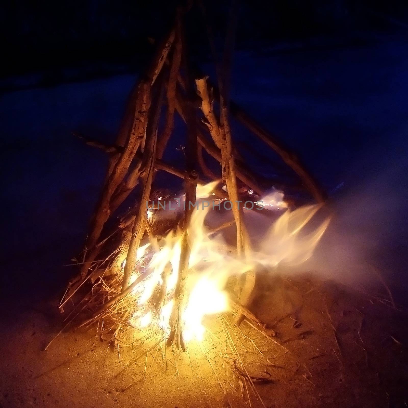 a small bonfire blazes in the night
