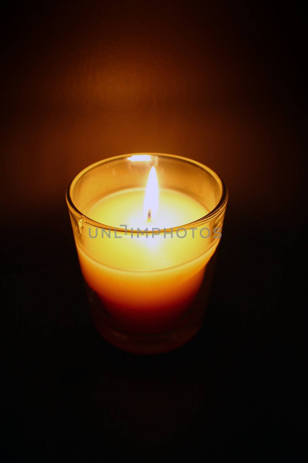 a candle blazes in a dark room