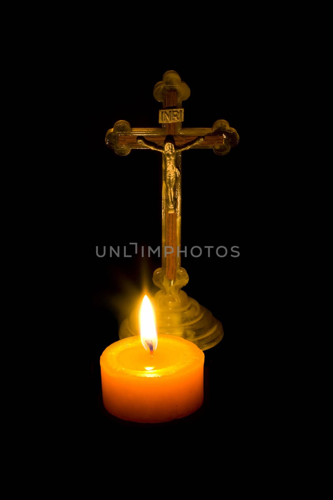 Cross stand behind a lit candle