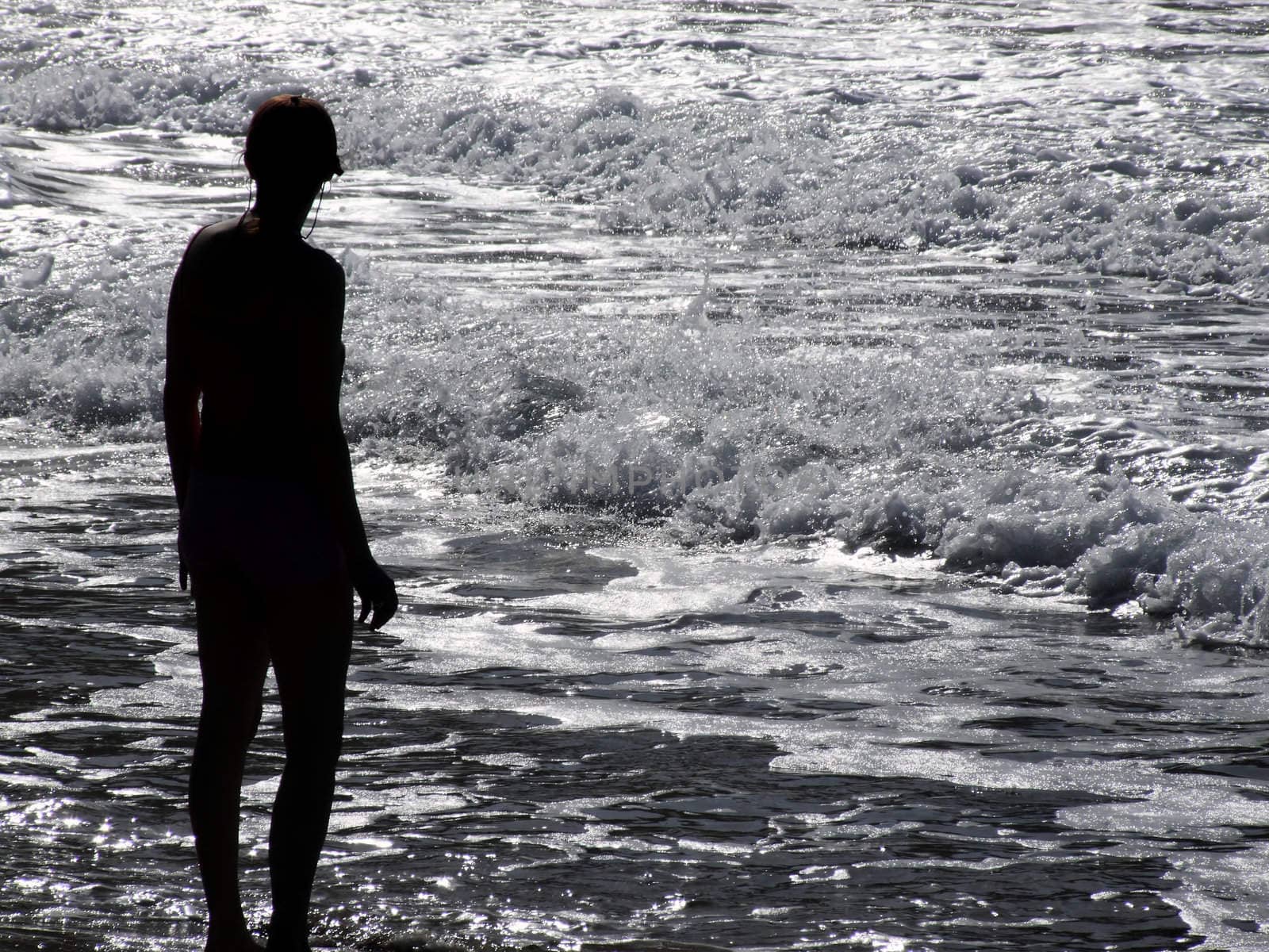 Silhouette of athletic woman watching glistening waves of the ocean