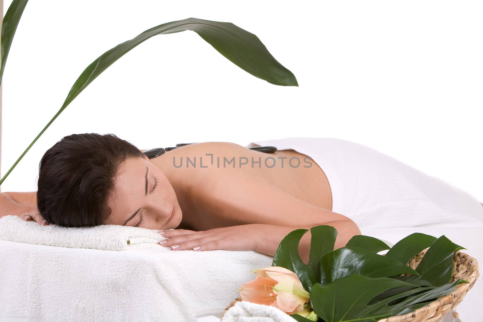 beautiful woman lying with a bare back covered with hotstones on a massage table