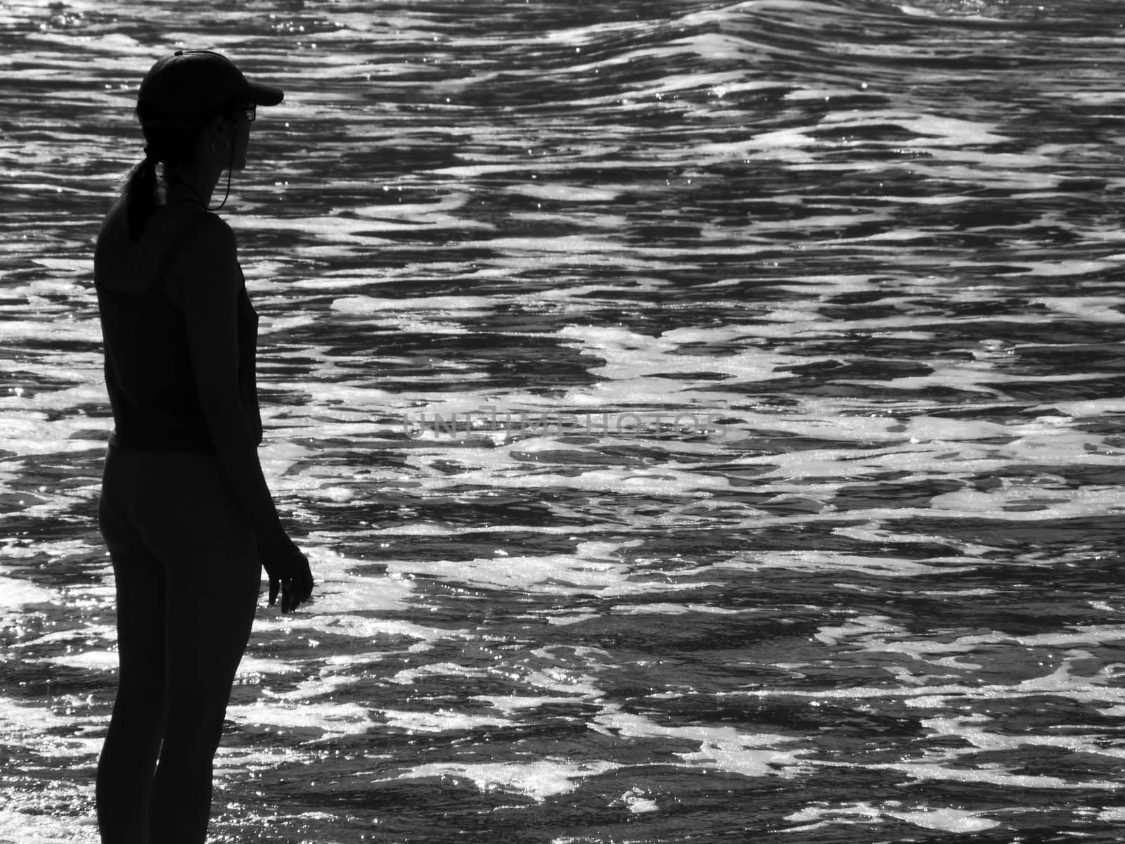 Silhouette of athletic woman watching glistening waves of the ocean