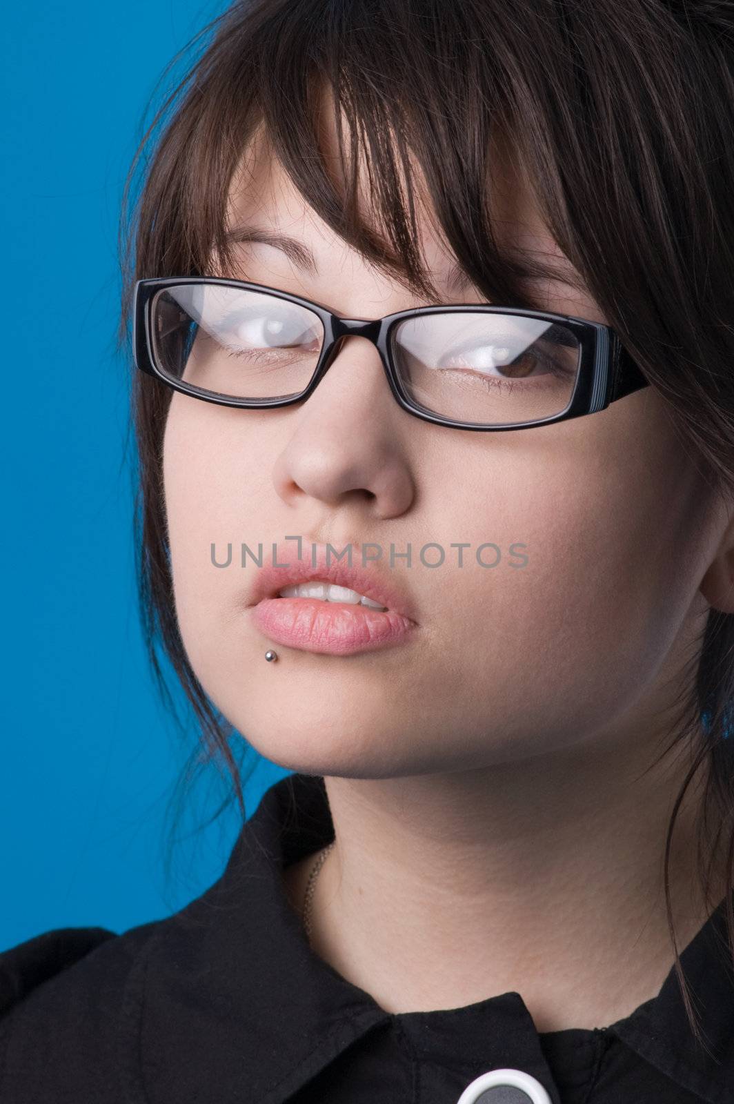 The girl on a dark blue background tries on glasses.
