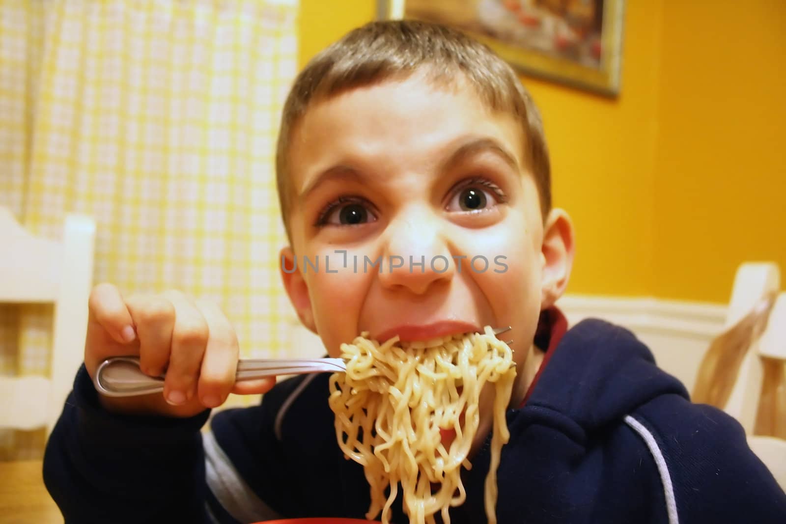 a goofy boy eating noodles
