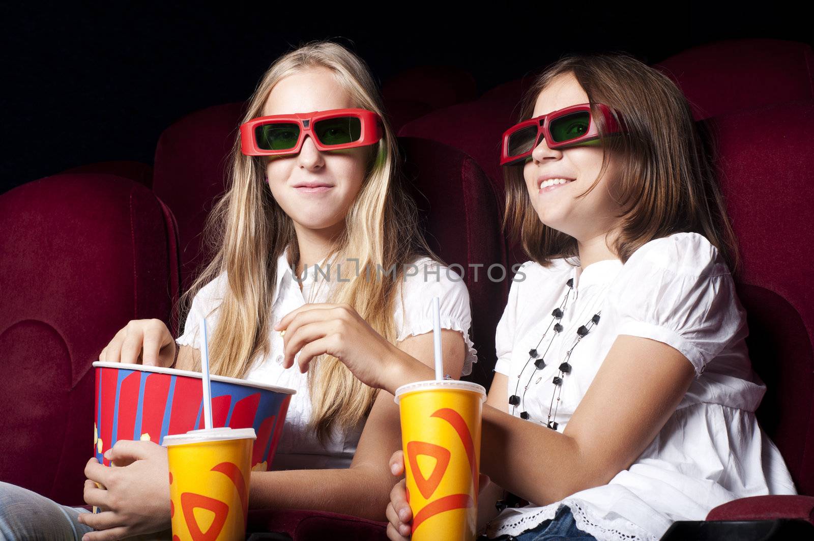 two beautiful girls watching a movie at the cinema by adam121