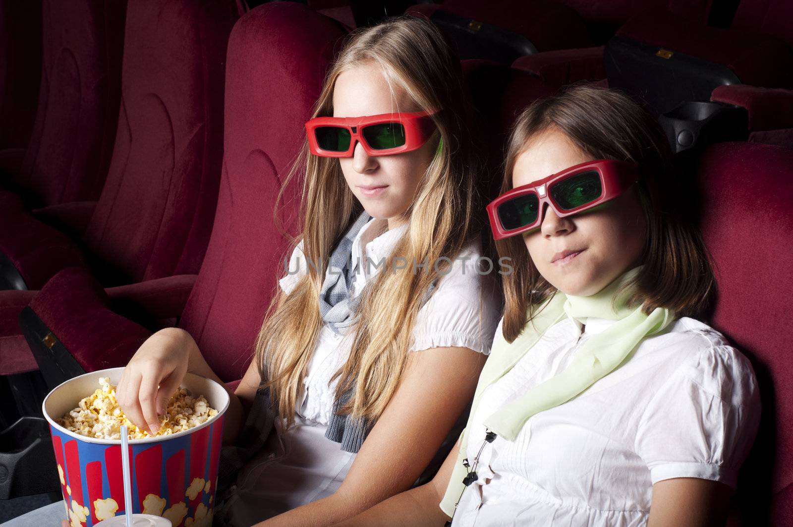 two beautiful girls watching a movie at the cinema by adam121