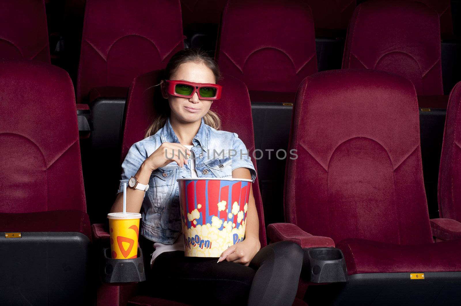 young woman sitting alone in the cinema and watching a movie