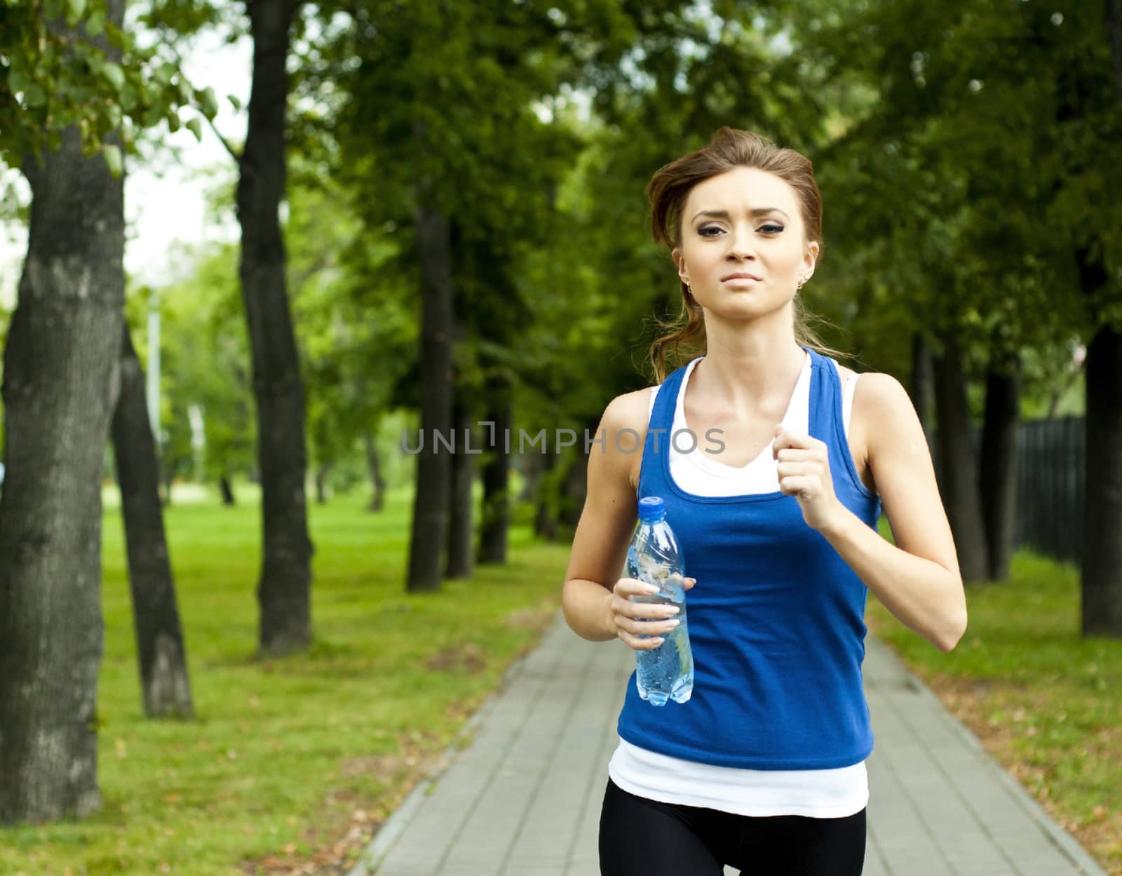 young woman run in the park in summer, trees and grass background