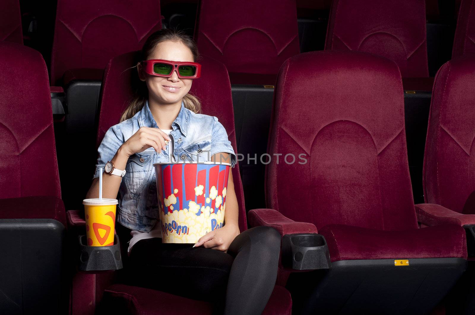 young woman sitting alone in the cinema and watching a movie