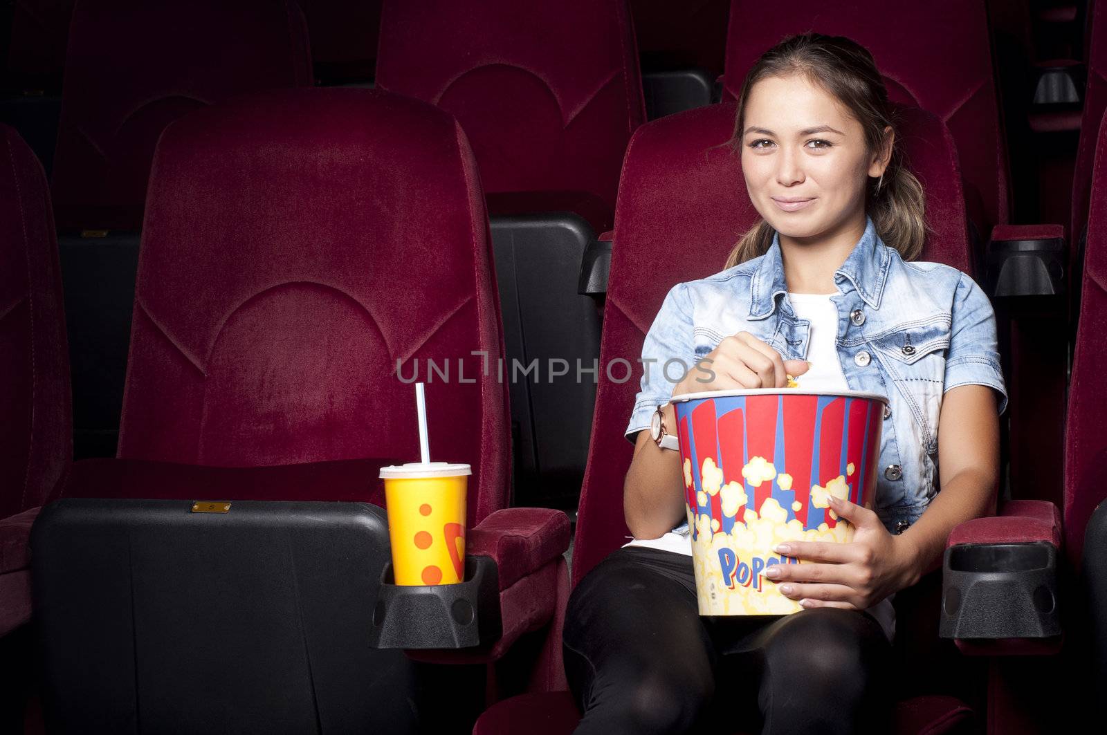 young woman sitting alone in the cinema and watching a movie