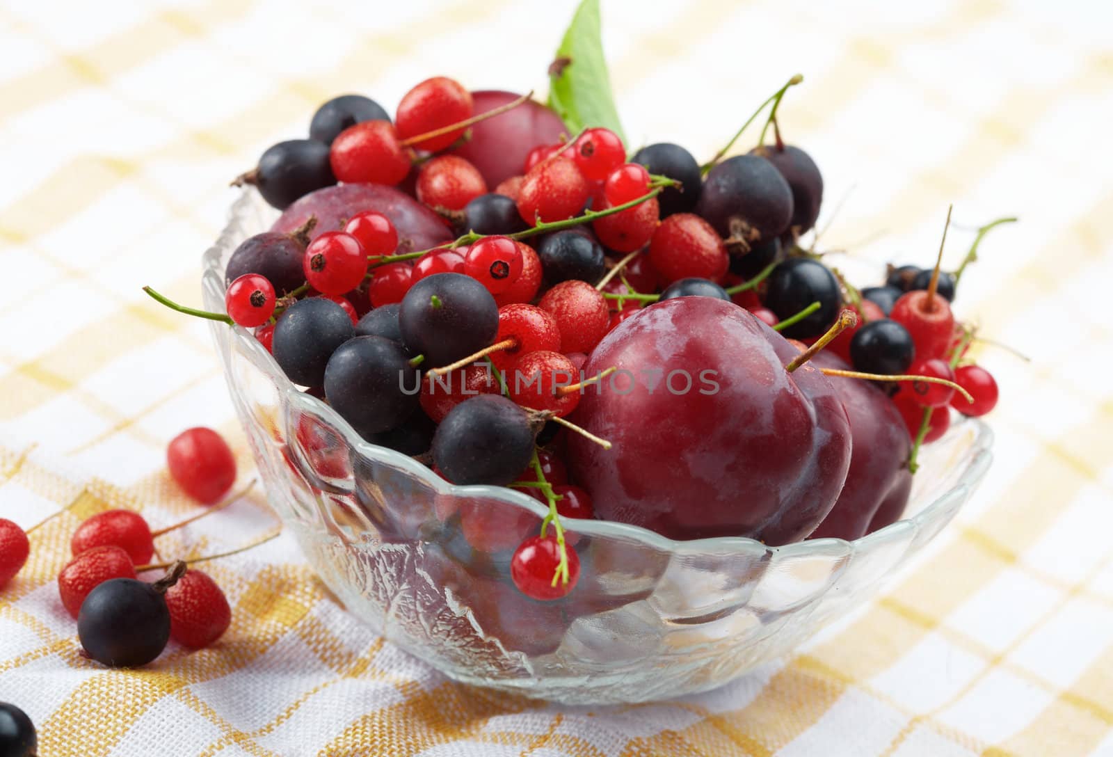 Mixed summer splitted berries in a cristal bowl on white