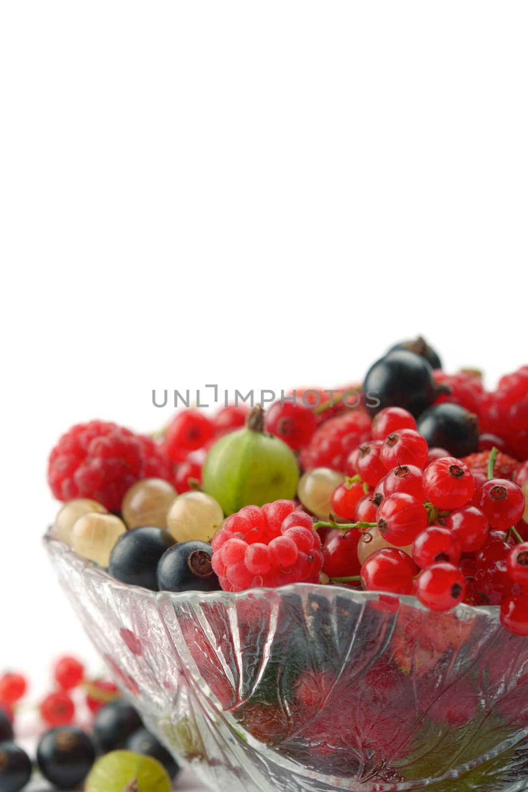 Mixed summer splitted berries in a cristal bowl on white