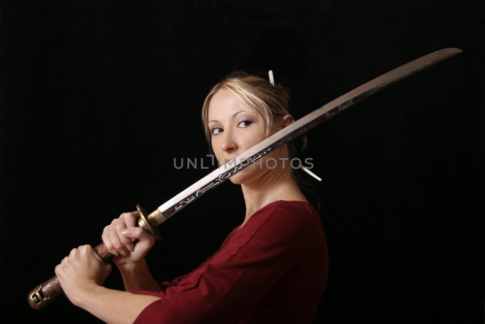 Young female grips a samurai sword, eyes fixed on opponent.