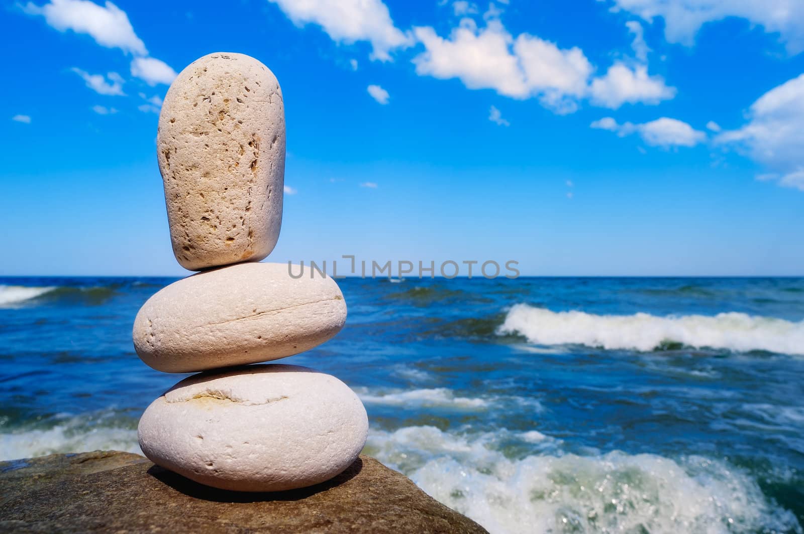 Three white pebbles against the background of the sea and sky