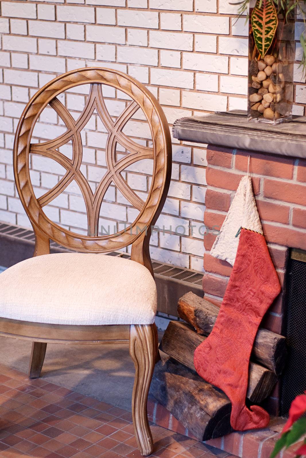 A Christmas stocking hung by the fireplace with a wooden chair beside it