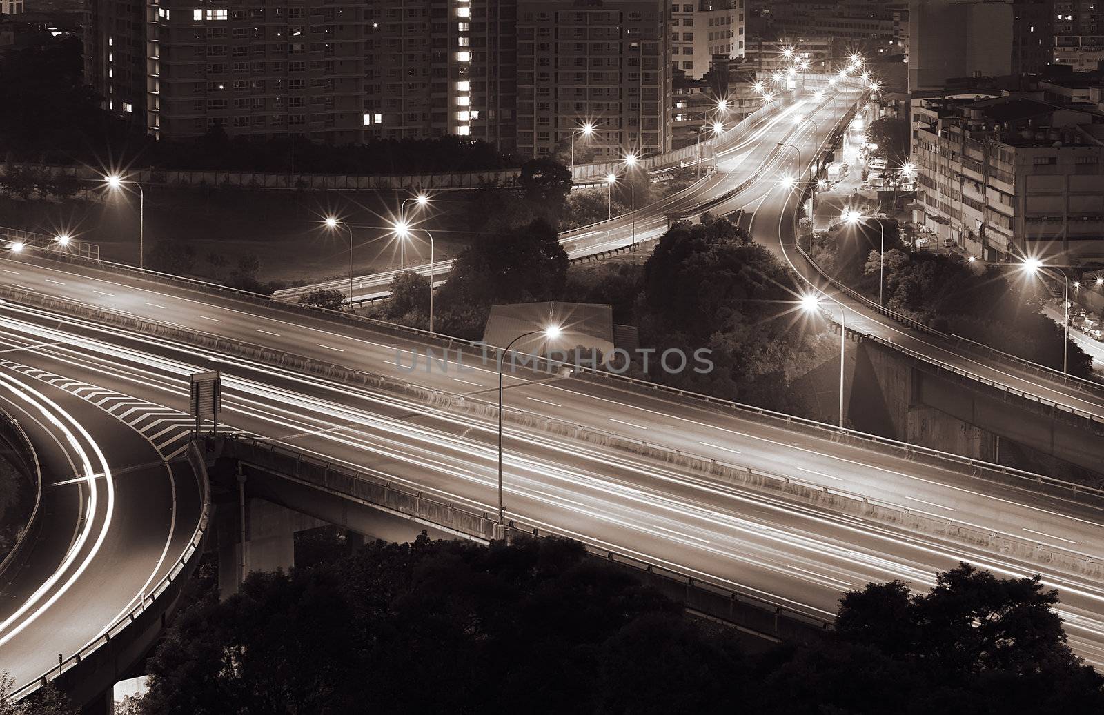 Traffic interchange night scene in modern city with cars light with dark buildings.