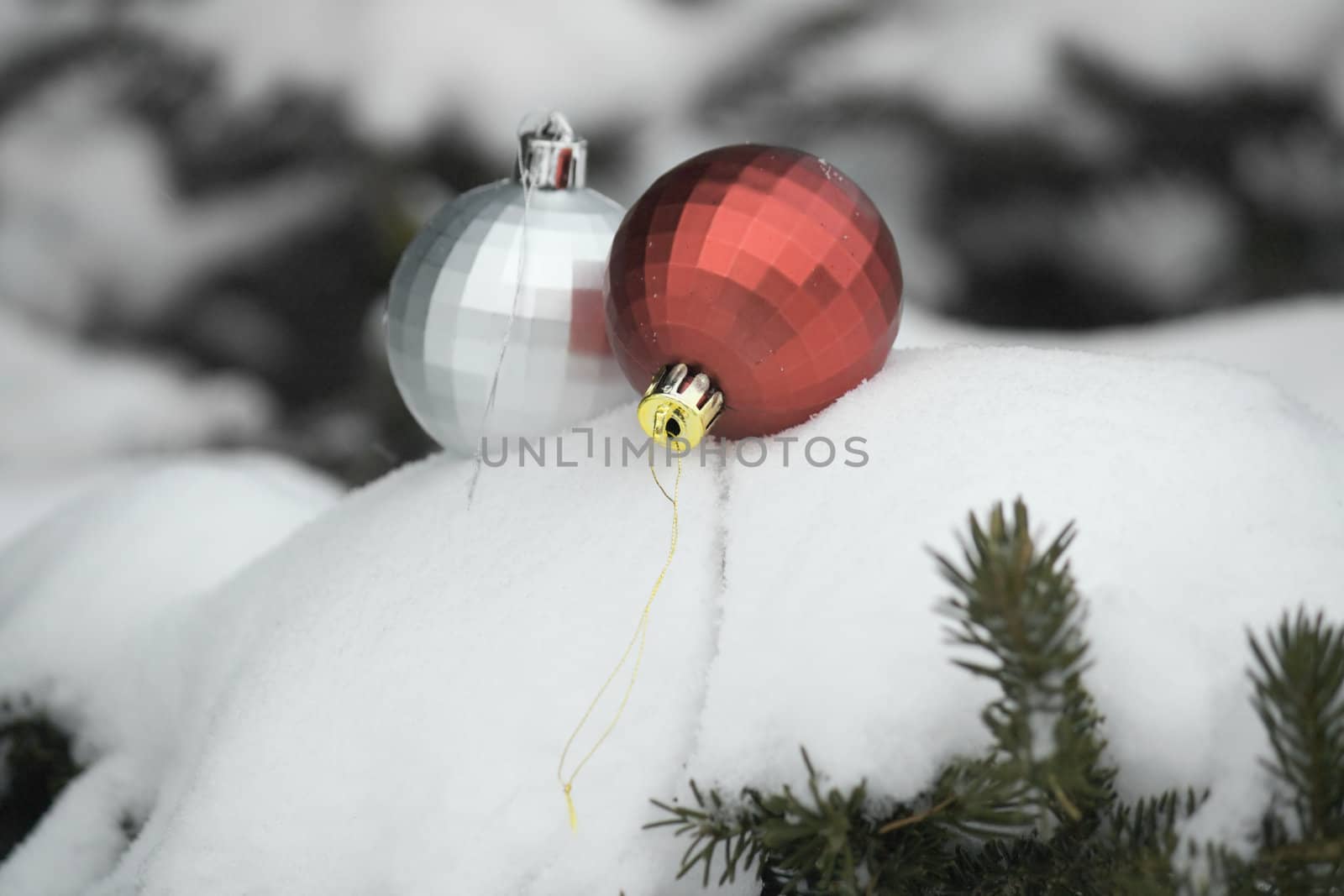 Bright Christmas balls lie on the snow on the branches of green pine.