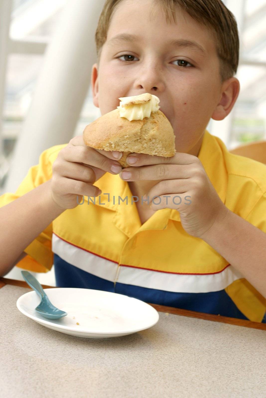 Child eating a banana muffin. 
Focus on hands muffin.

