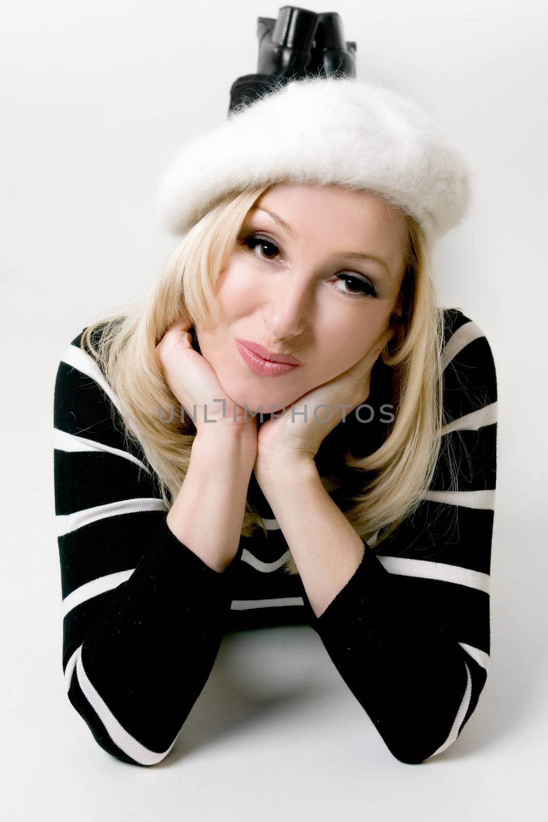 A relaxed casual dressed woman in jeans, sweater and angora beret lies daydreaming good thoughts or memories or perhaps watching tv or movie, etc.