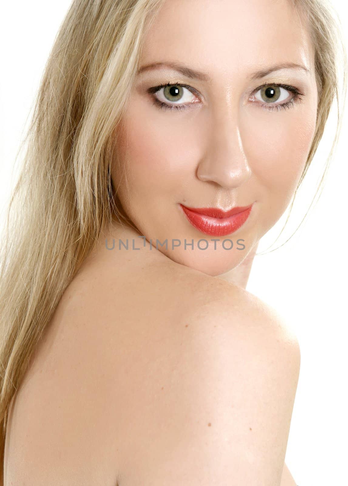 Fresh faced, beautiful woman with green eyes and long blonde hair looking over bare shoulder