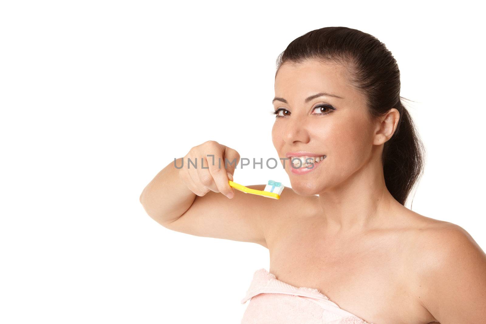 A female wrapped in a pink towel holding a toothbrush with toothpaste and smiling.