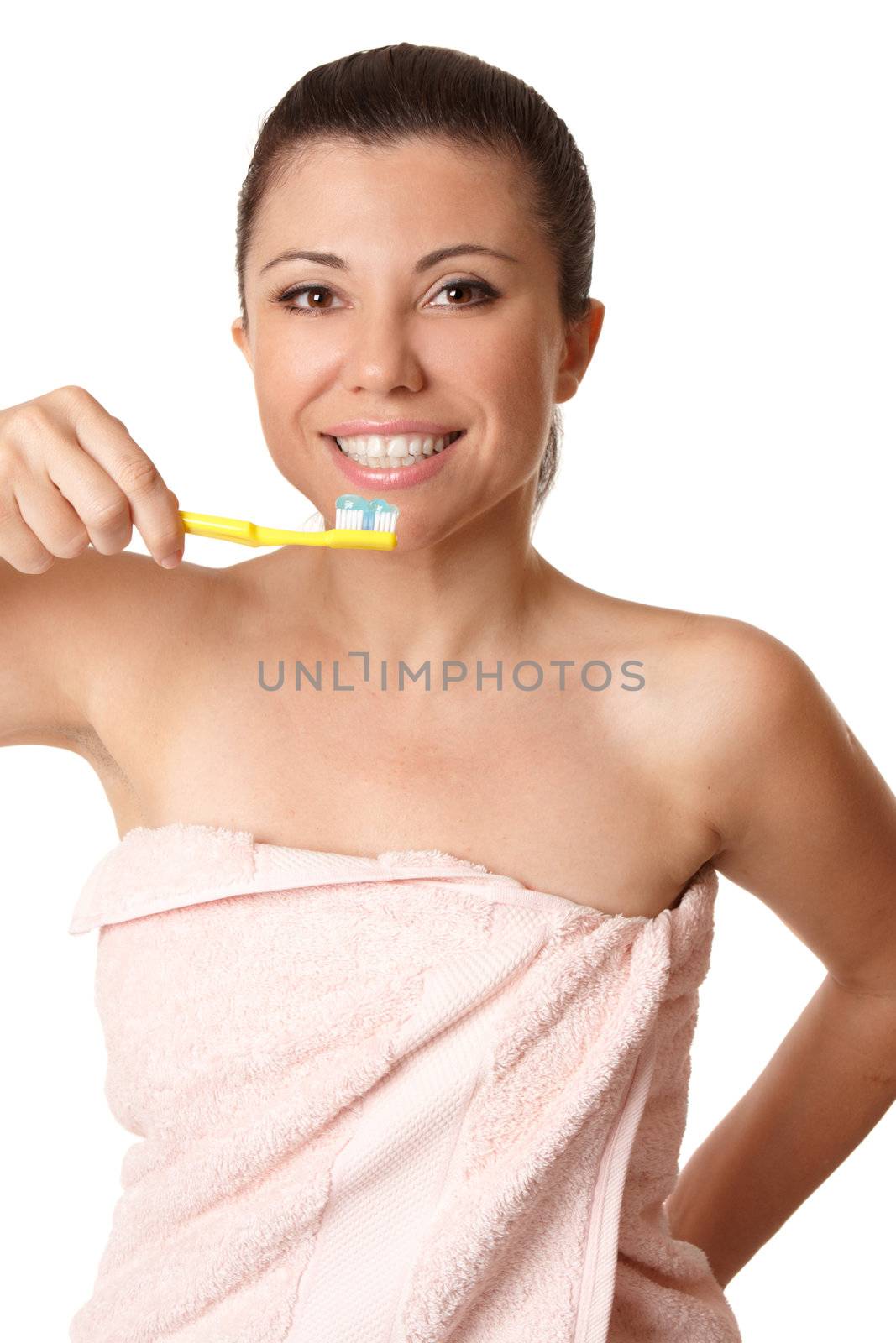 Smiling woman holding a toothbrush with toothpaste about to brush her teeth.