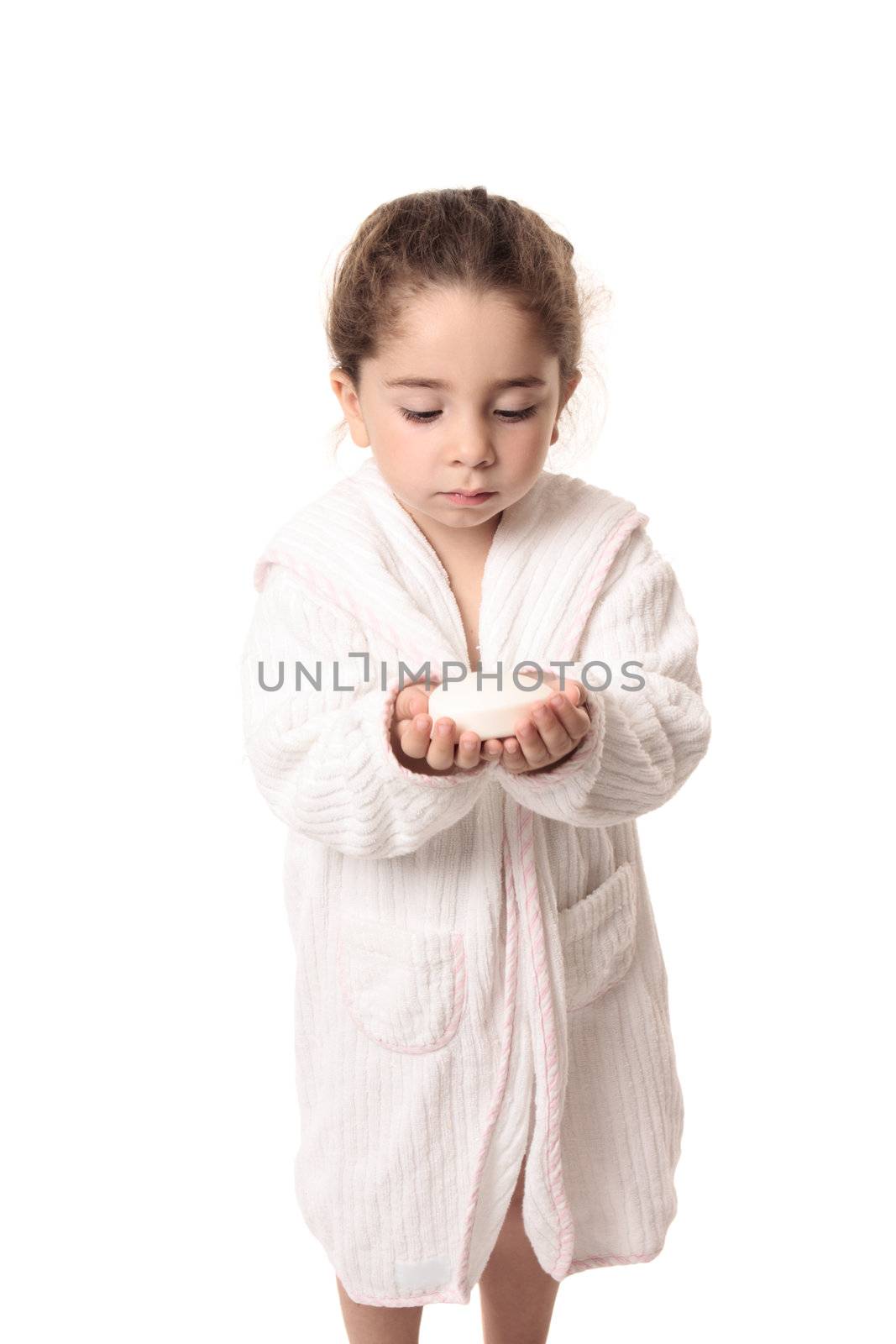 Little girl in white bathrobe holding a bar os soap in her hands.