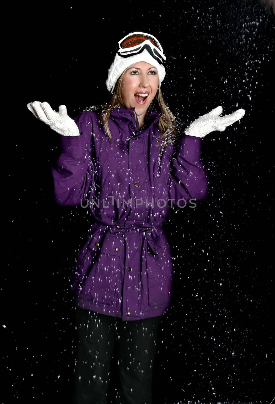 A woman wearing a warm parka, beanie and gloves enjoys the soft falling snowflakes.   Motion in flakes