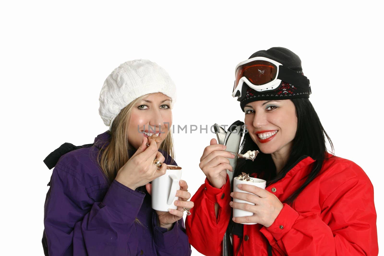 Two girls enjoy hot drinks finished with cream toppings.