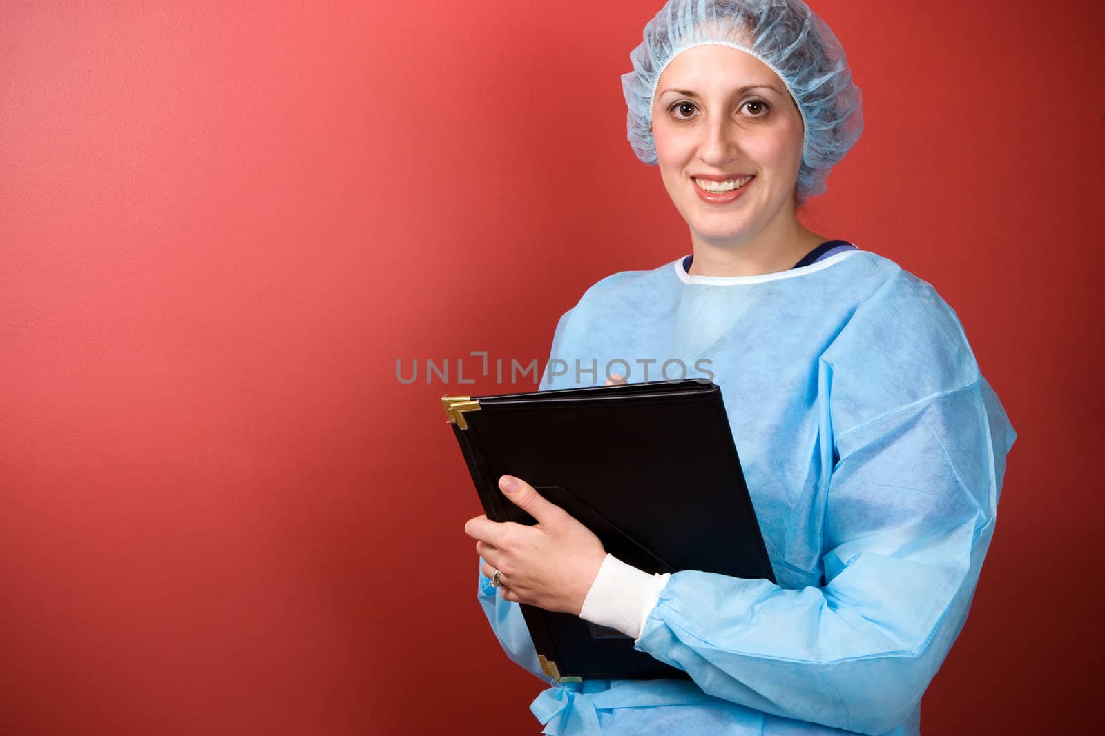 A young healthcare professional posing over a solid red background.