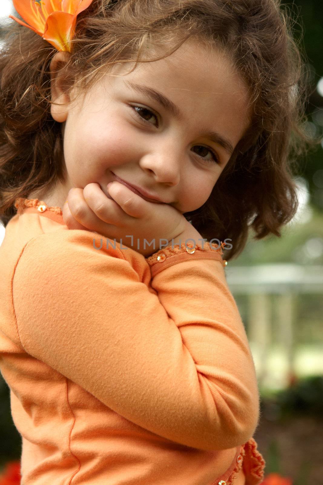 Pretty smiling preschool age girl outdoors in the shade of a tree.