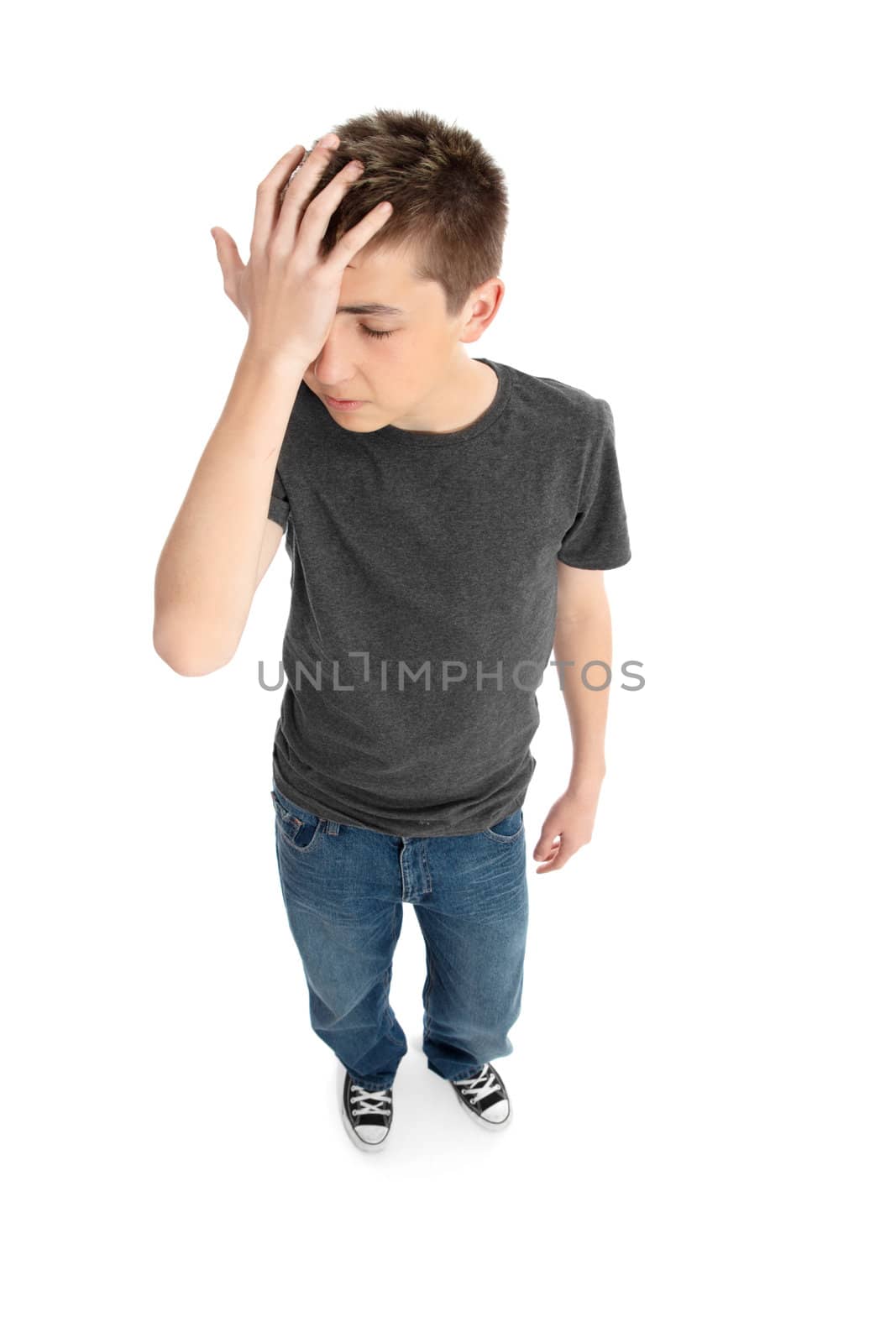 Pre teen boy with head in hand eg mistake, blunder, headache, worry, forgetfulness.  Shadow under feet.