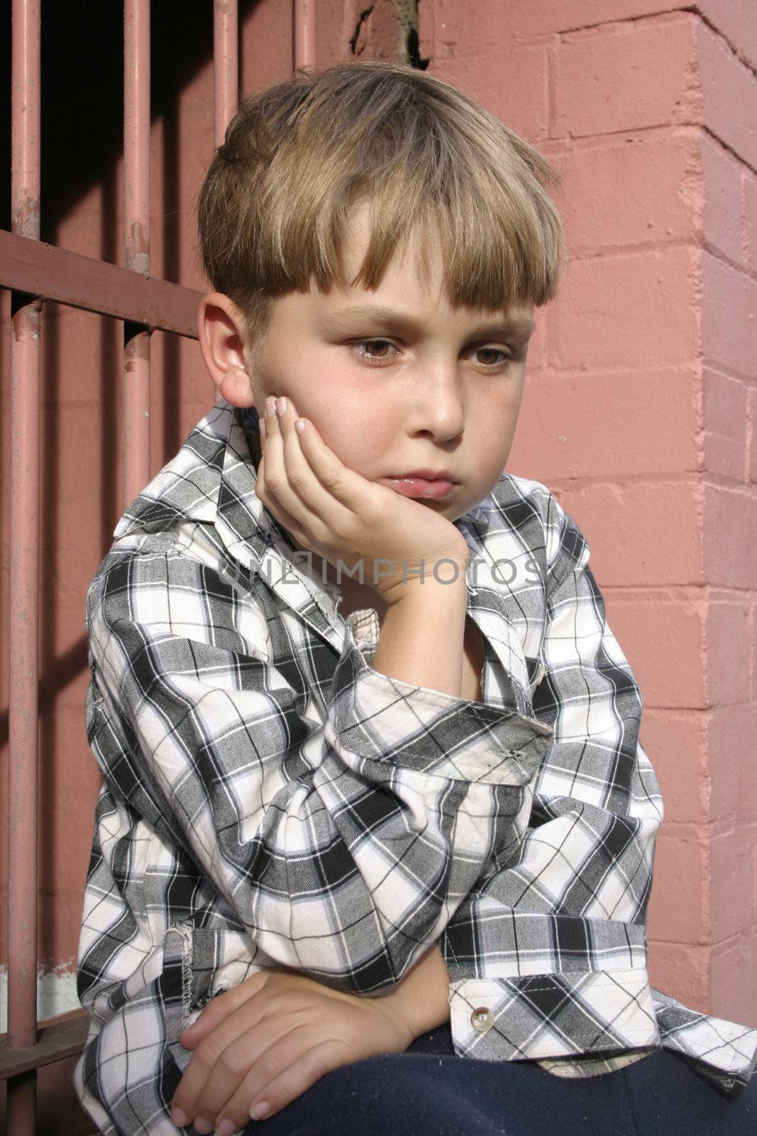 Boy in mismatched clothing looking sombre.  Part of a kids on the street series
