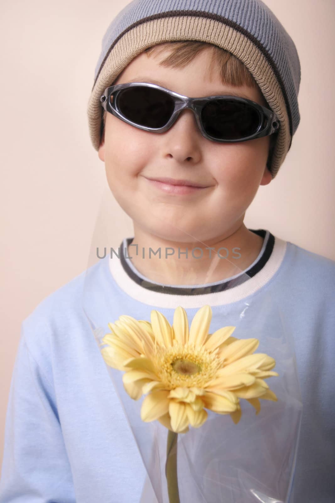 Boy holds a  gift of a creamy yellow gerbera.

