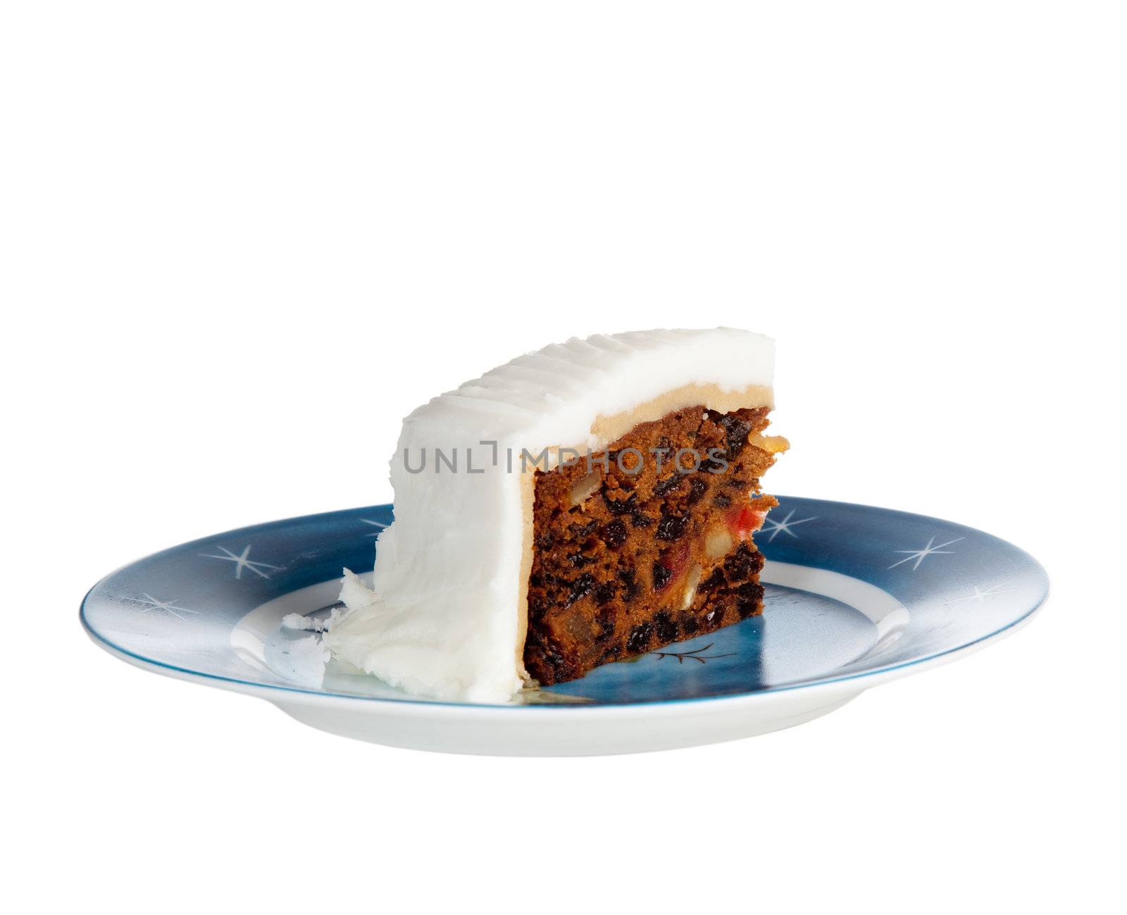 Triangular slice of traditional christmas cake on a blue starry plate