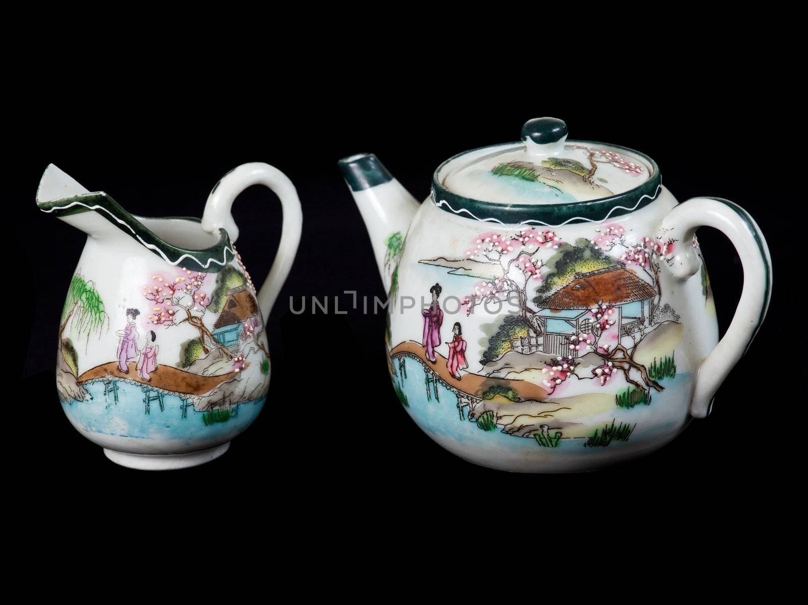 Old chinese decorated teapot and milk jug in traditional style isolated against black