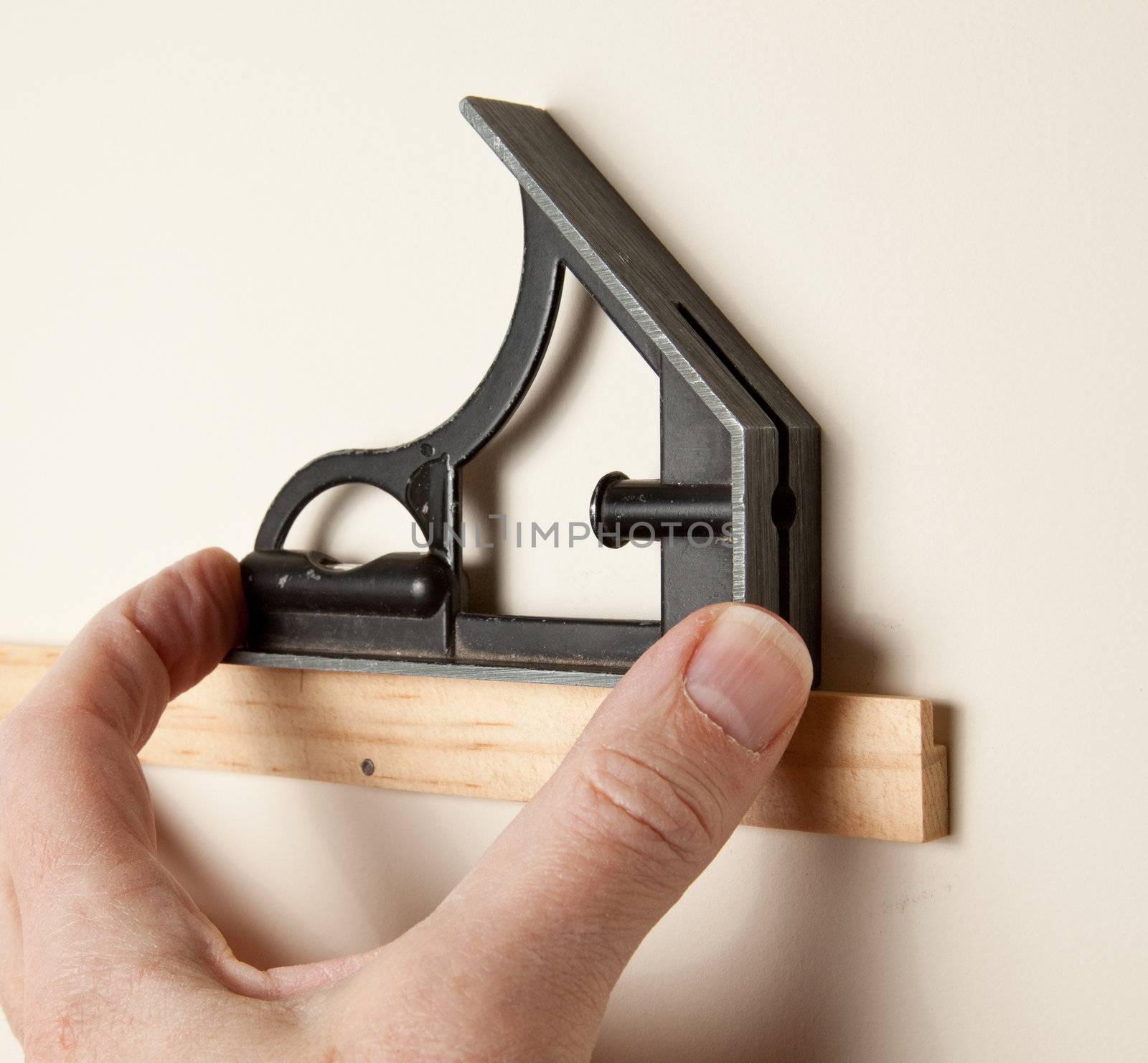 Using a triangular leveling tool to level a piece of wood on wall