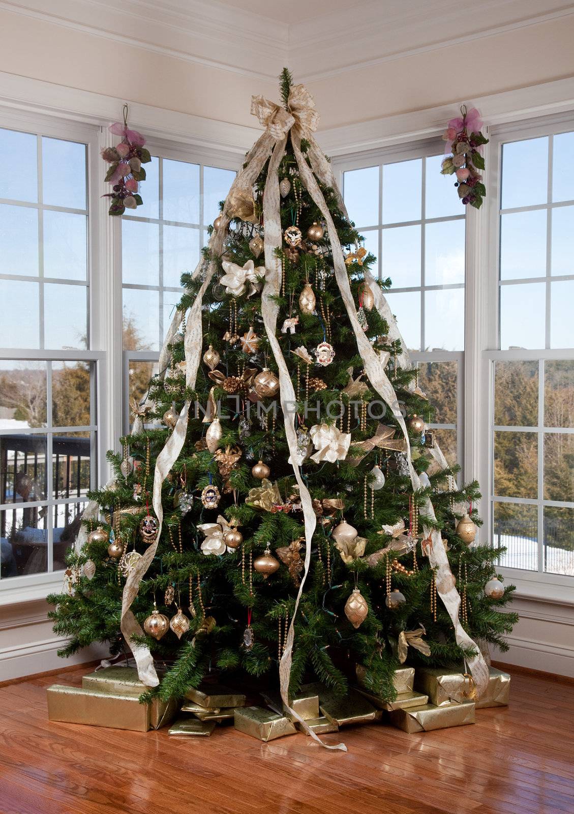 Beautifully decorated xmas tree in the corner of a large luxurious family room