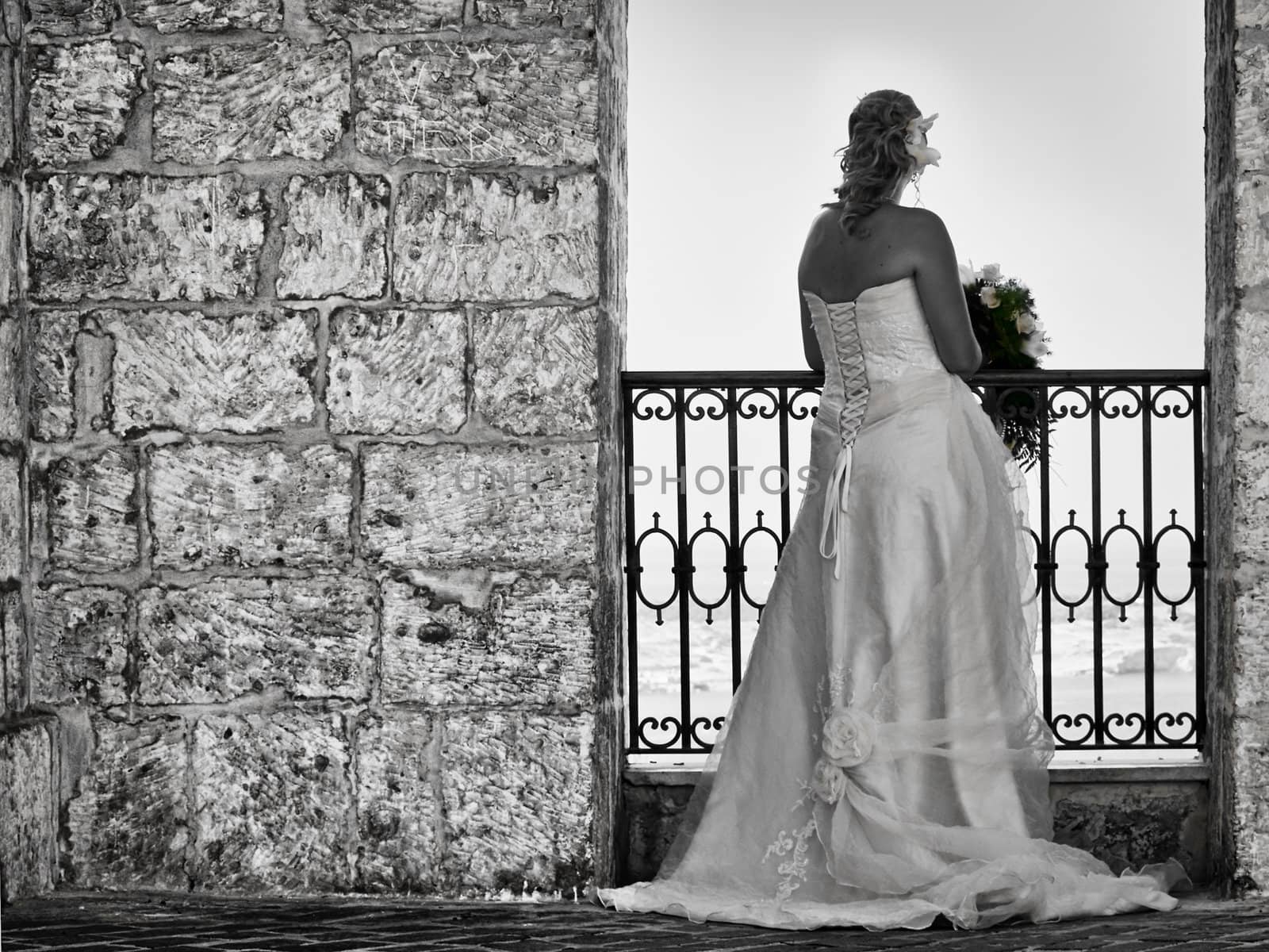 A newly wed bride in a medieval balcony overlooking Mellieha Bay in Malta