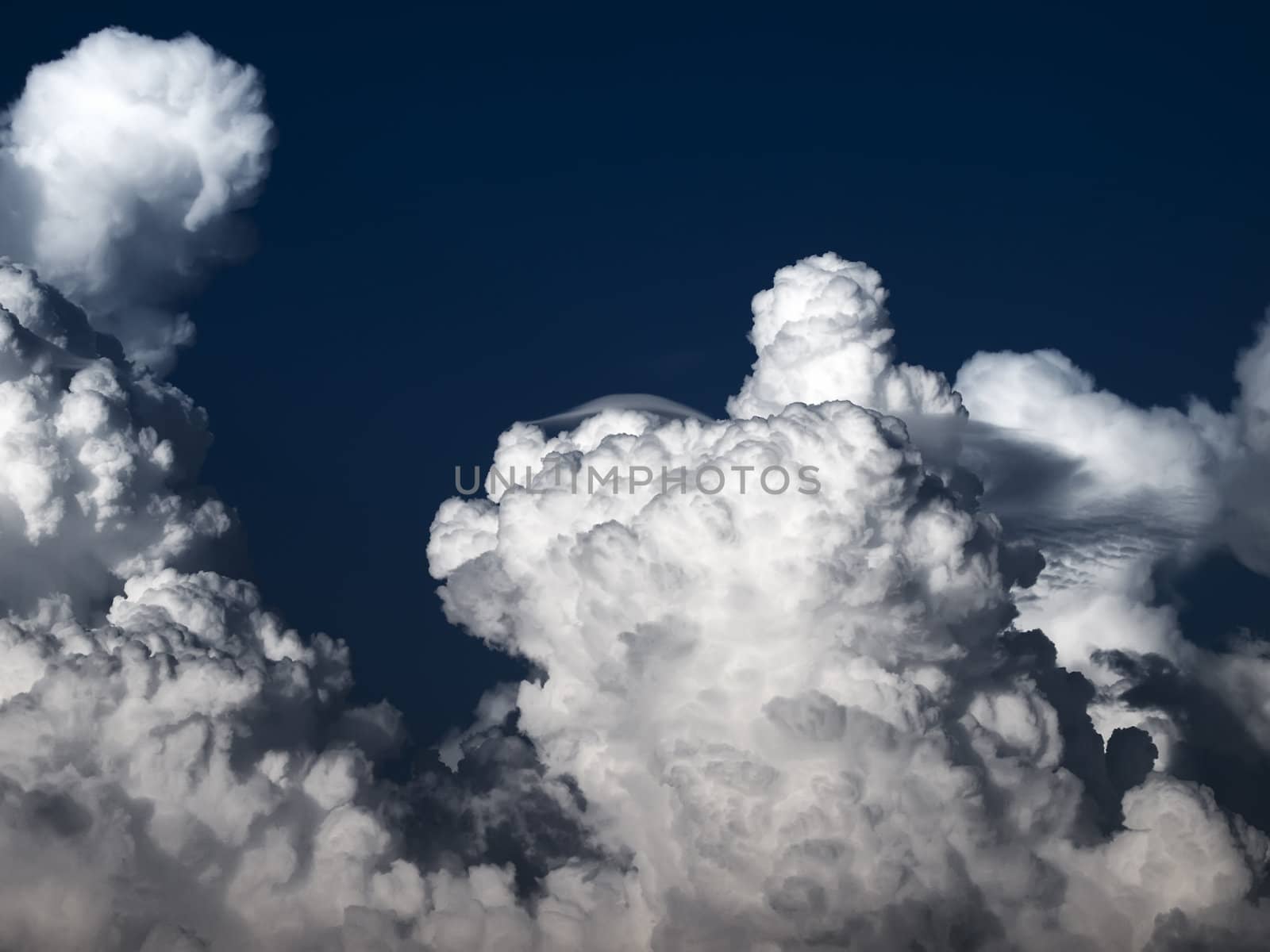 Towering detailed cumulus cloud with lenticular formations