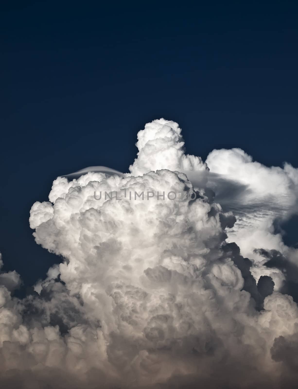Towering detailed cumulus cloud with lenticular formations