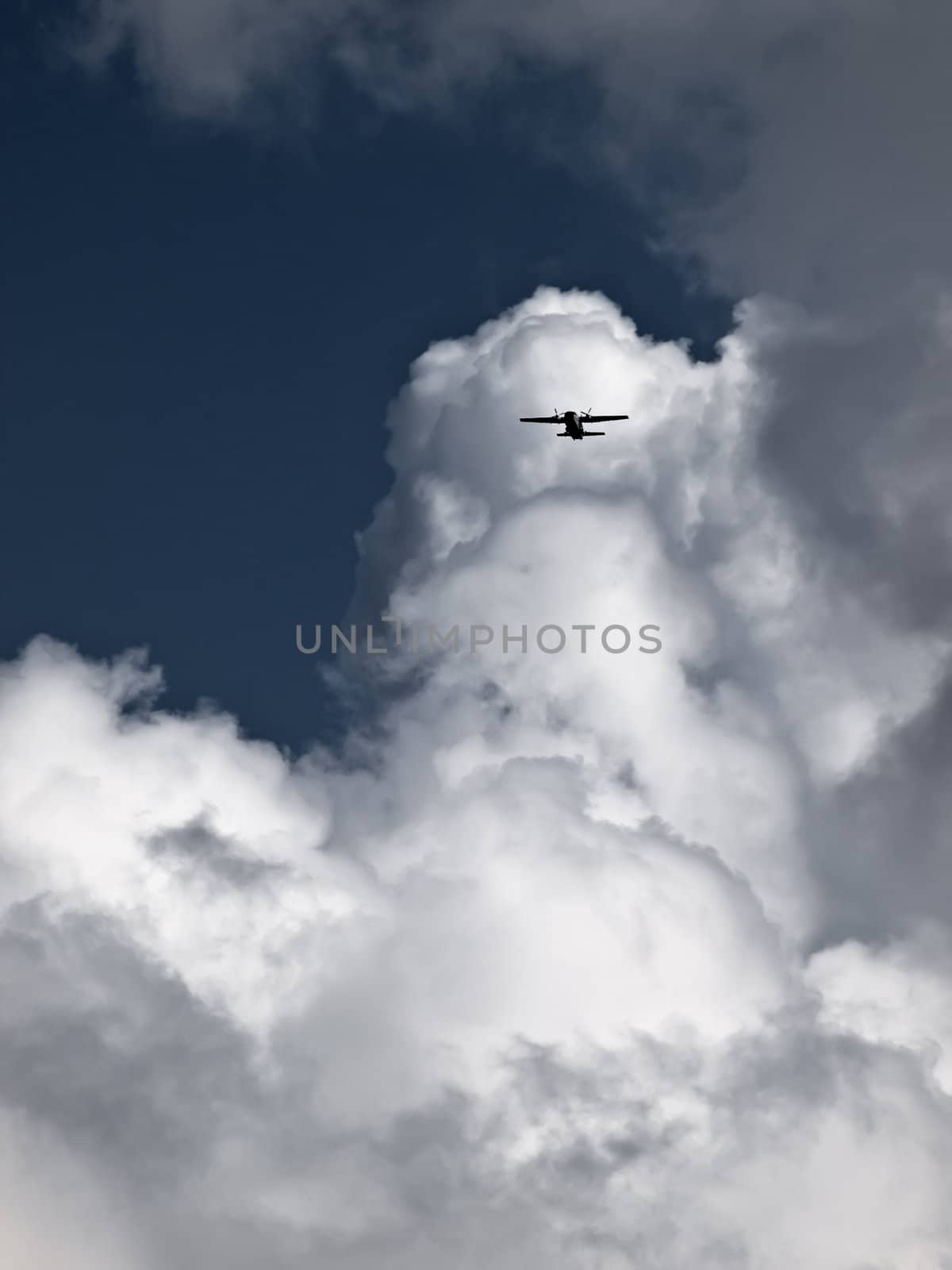 A turboprop aeroplane emerges from a large cumulus cloud