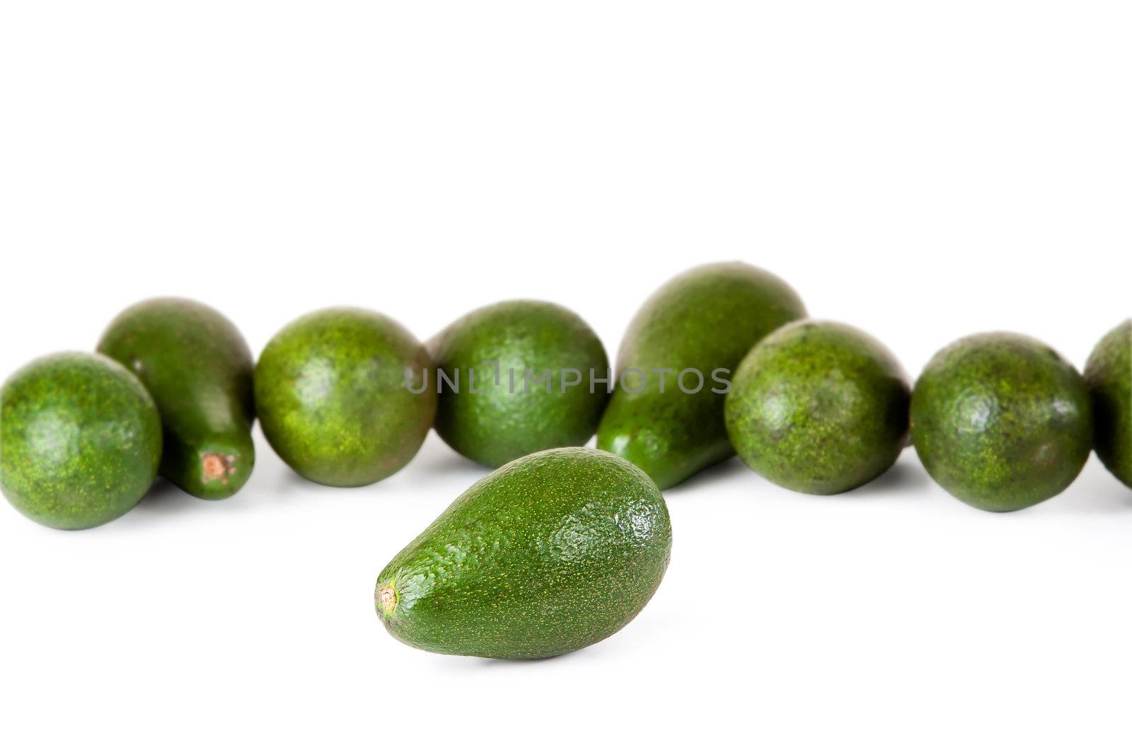 One avocado in front of several more on white background