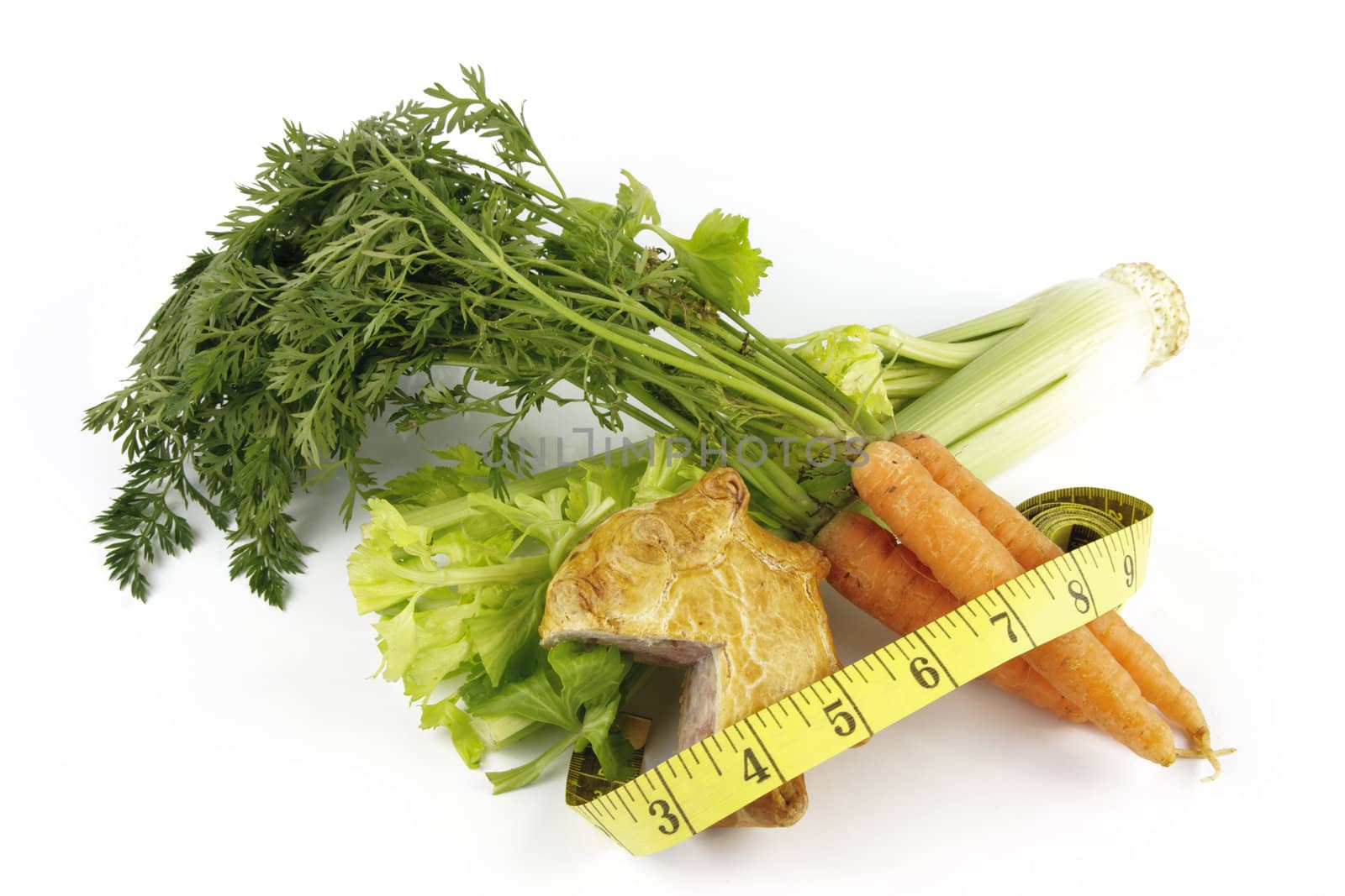 Contradiction between healthy food and junk food using a bunch of carrots and pork pie with a tape measure on a reflective white background 