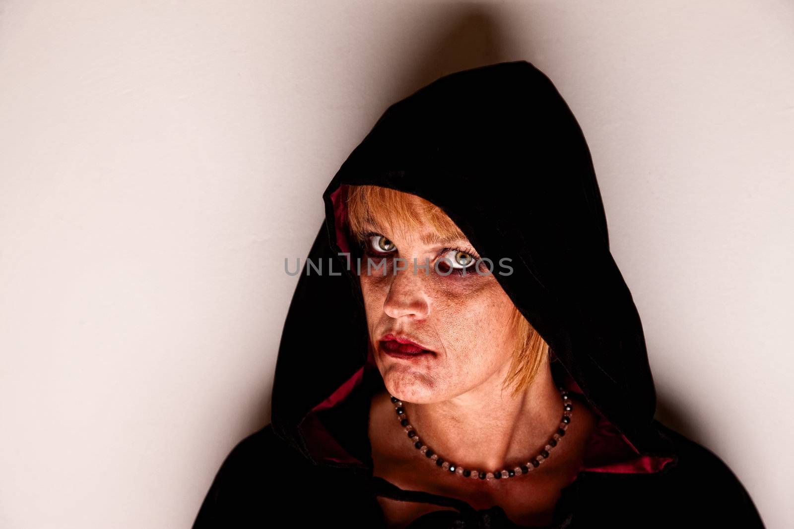 Witch in black hood standing in corner