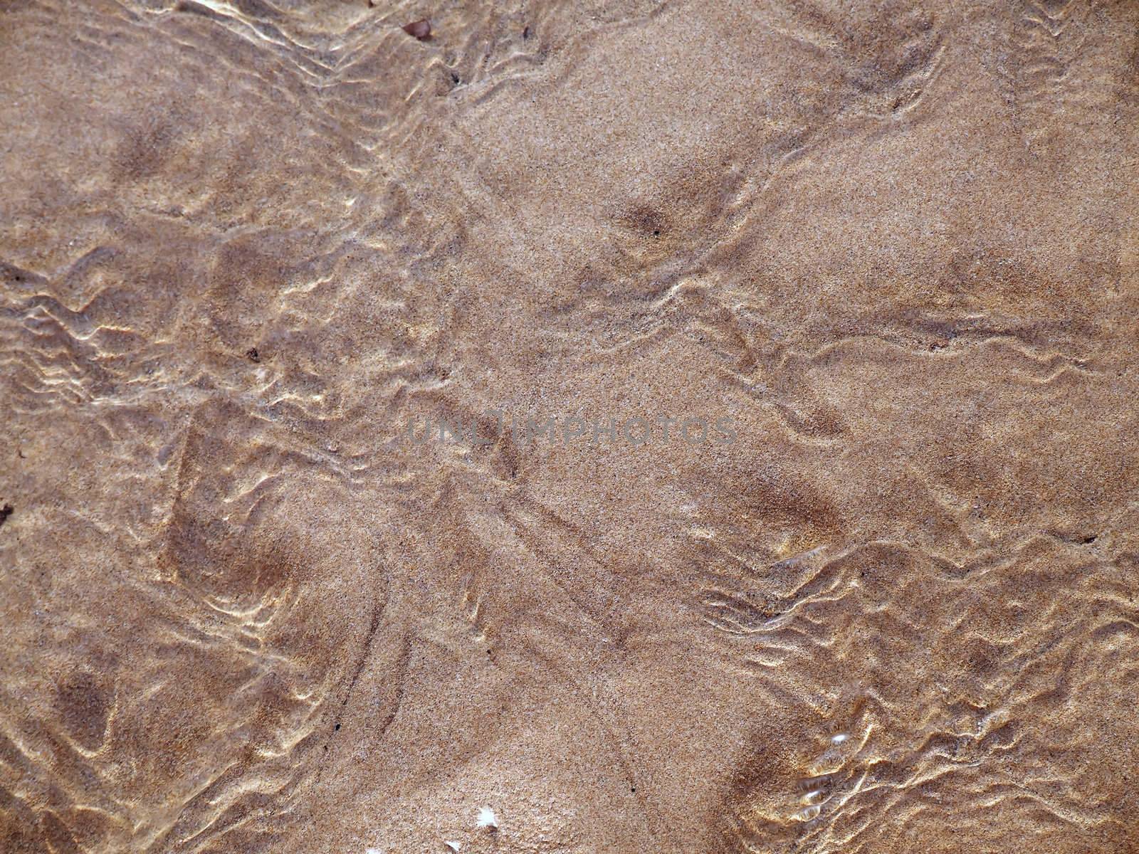 Shallow spring water flowing over sand on a beach in Malta